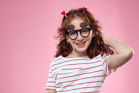 Cheerful girl with pigtails sunglasses striped t-shirt lifestyle pink background