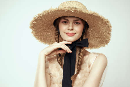 Nice girl in a straw hat with a black ribbon and in a dress on a light background romance model fun emotionの写真素材