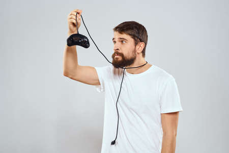 A man with a gamepad in his hands playing games leisure lifestyle technology white t-shirt light...