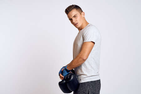 Strong man with boxing gloves and in a white t-shirt on an isolated background cropped view of the modelの写真素材