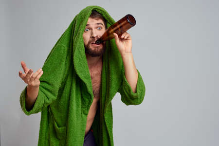 drunk man with bottle of alcohol in hand and green robe drinking relaxationの写真素材