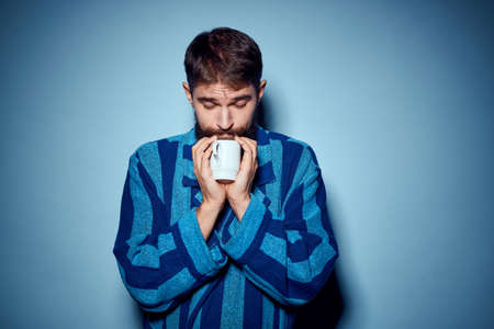 man in striped blue robe holding white cup in hand and emotions fun surprise model cropped viewの写真素材