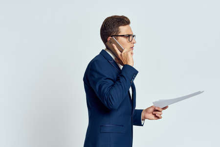 Business man in a suit talking on the phone with glasses with documents technology officialの写真素材