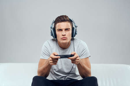 A man in headphones sits on the couch mobile game console hobby entertainmentの写真素材