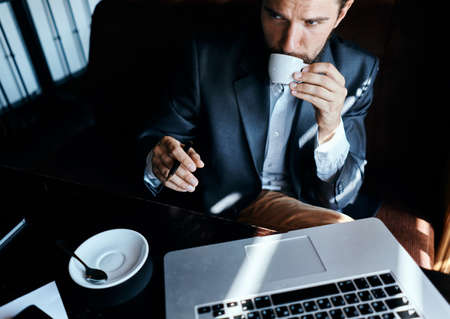 Business man sitting in a cafe in front of a laptop with a cup of coffee work technology lifestyleの写真素材