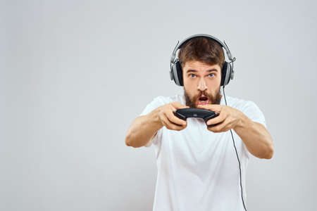 Man in headphones with gamepad playing hobby entertainment lifestyle light background