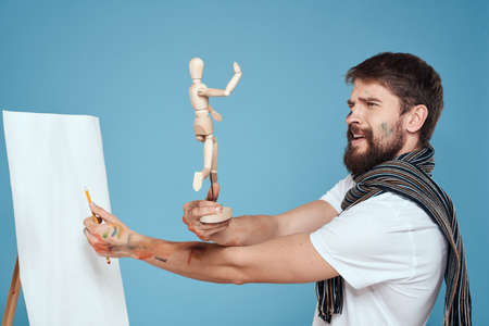 Male artist with a wooden dummy in hands drawing Creative hobby blue backgroundの写真素材