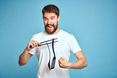 Bearded man with tools for cooking on a blue background and a white T-shirt shovel