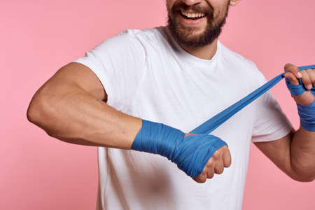 Sporty man in a white T-shirt boxing bandages on the hands of a workout lifestyle pink backgroundの写真素材