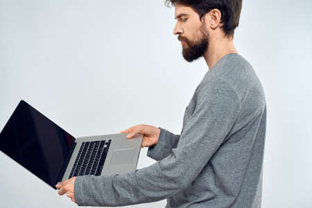 A man in a gray sweater with a laptop hands lifestyle technology communication internet workの写真素材