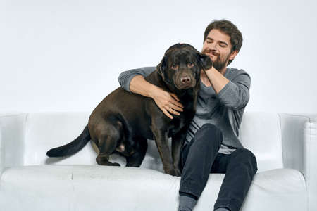 Man with a pet dog on the couch fun friends emotions light roomの写真素材