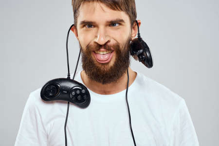 A man holds in his hands two joysticks playing leisure technology lifestyle white t-shirtの写真素材