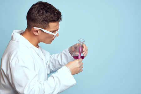 man holding flasks colorful liquid chemical laboratory model wearing glassesの写真素材