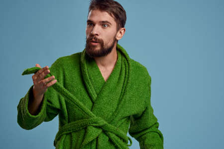 Bearded man in green robe with belt on blue background cropped view of emotionの写真素材
