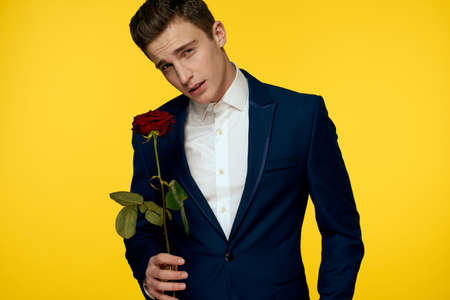 Gentleman in classic suit on yellow background with red rose romance