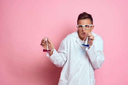 Male laboratory assistant with flasks in the hands of a multicolored liquid chemical substanceの写真素材