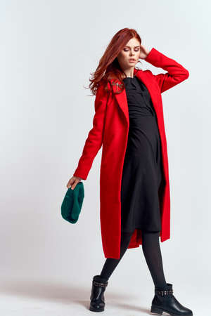 emotional woman in a red coat and with a hat in full growth on a light background black boots pose modelの写真素材