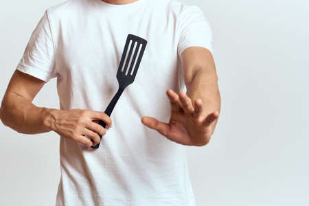man with shovel for cooking white t-shirt cropped view light backgroundの写真素材