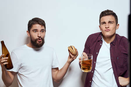 Two cheerful friends drinking beer drunk fun lifestyle communication light background