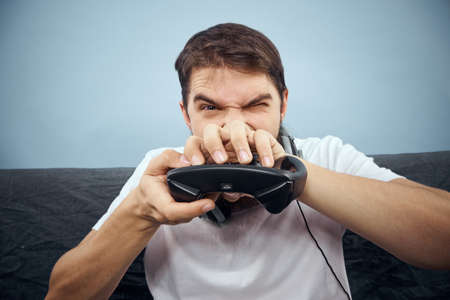 A man sits on a sofa with a gamepad in his hand. Leisure lifestyle game consoleの写真素材