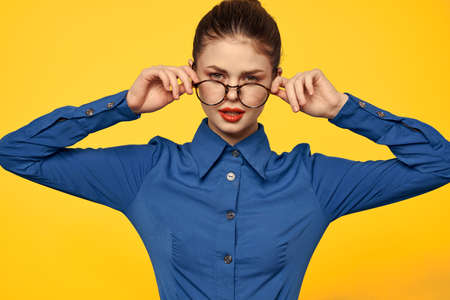 A woman in a blue shirt and glasses with bright makeup on her face is gesturing with her hands Copy Spaceの写真素材