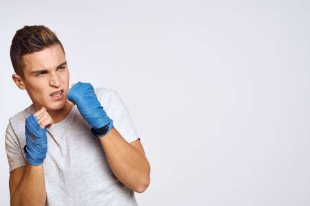 sporty male boxer in blue gloves practicing punches on a light background cropped viewの写真素材