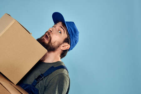 working man boxes in hands delivery service packaging lifestyle blue backgroundの写真素材