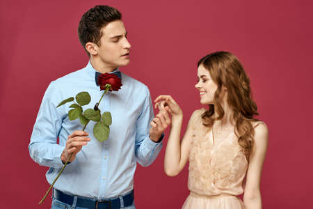 enamored man and woman with a red flower on a pink background hug each other Copy Spaceの写真素材
