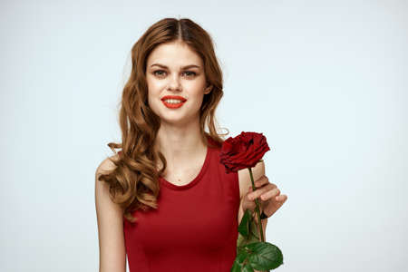 Beautiful woman in a red dress holds a rose in her hand a gift flowers decoration attractive look