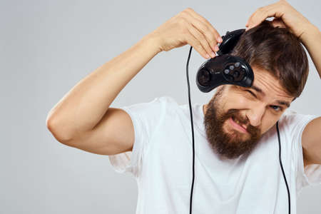 A man holds in his hands two joysticks playing leisure technology lifestyle white t-shirtの写真素材