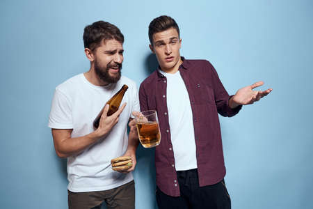 Two cheerful drunk friends drinking beer lifestyle emotions on a blue background