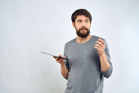 A man with a tablet in his hand internet technology communication gray jacket light backgroundの写真素材