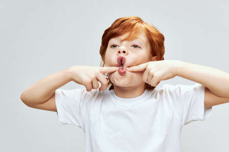 portrait of redhead child holding hands on cheeks with open mouth studioの写真素材