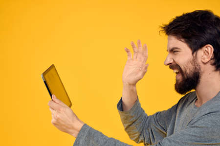 Bearded man with tablet in hands technology work wireless device yellow backgroundの写真素材