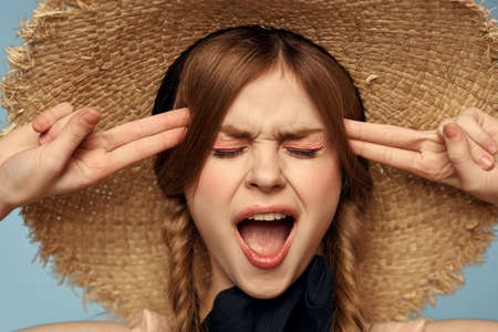 Girl in a straw hat portrait close-up pigtails fun red hair blue backgroundの写真素材