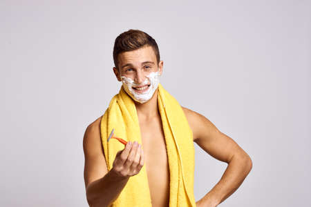 A man with a yellow towel on his shoulders and an orange razor white foam clean skin