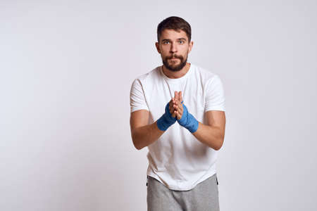 sports man in white t-shirt blue boxing bandages on his arms workout exercisesの写真素材