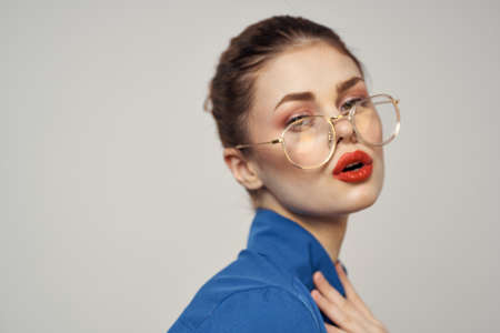 Portrait of emotional woman in blue shirt and glasses bright makeup model light background cropped view Copy Spaceの写真素材