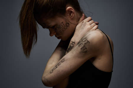 upset woman with offensive writing on her body on gray background touching herself with hands...