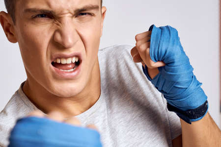 sporty male boxer in blue gloves practicing punches on a light background cropped viewの写真素材