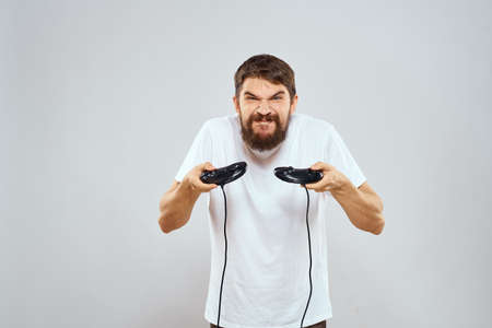 A man holds in his hands two joysticks playing leisure technology lifestyle white t-shirtの写真素材