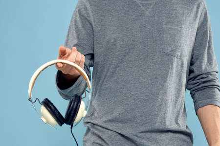 Headphones in man hands cropped view music technology blue backgroundの写真素材