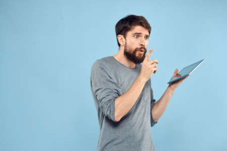 Emotional man with a tablet in the hands of a wireless device internet technology lifestyle blue backgroundの写真素材