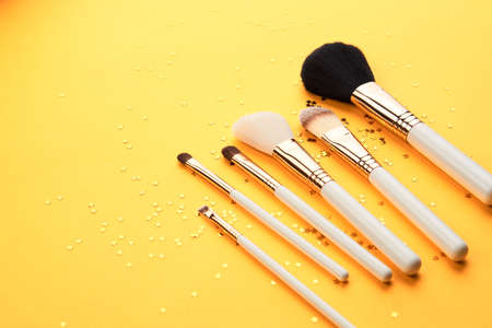 Makeup brushes in different sizes on a yellow background and glitter cropped lookの写真素材