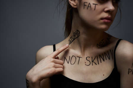 Emotional woman with inscriptions on her body gestures with hands lifestyle frustration stress gray backgroundの写真素材