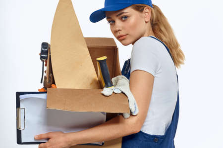 Woman working with box in hands of tools delivery service light backgroundの写真素材