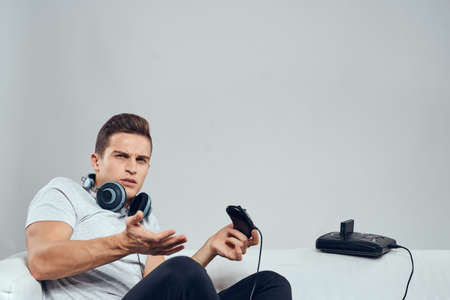 A man sits on the couch with headphones a video game set-top box entertainment fun