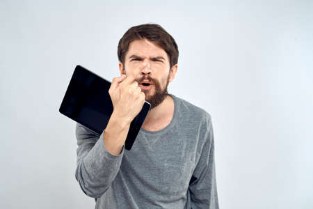 emotional man holding tablet technology communication internet work light backgroundの写真素材