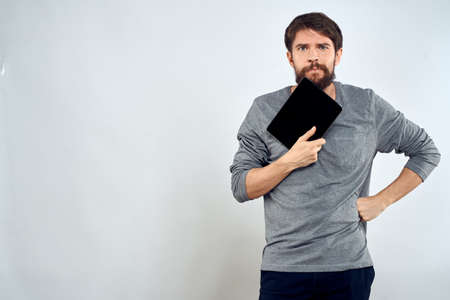 A man in a gray sweater a tablet in the hands of emotions Internet technology lifestyle light...