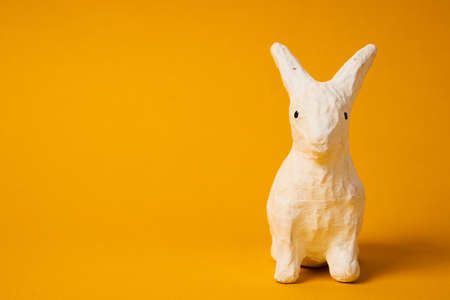 White Easter bunny on a yellow background animal decoration Copy Space